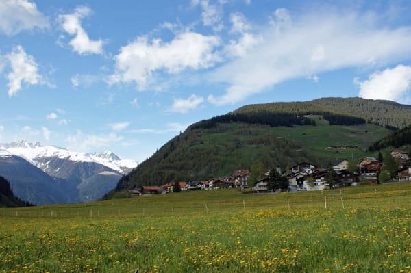 Curaglia, a village in the Val Medel in the Grisons: its houses, spring meadows and the mountains