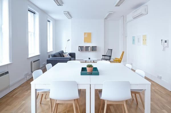Illustrative photograph: a bright workspace, with a large table, chairs and a lounge corner. It is not a space we offer.
