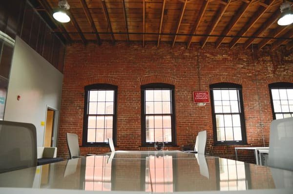 Illustrative photograph: a commercial space, with a brick wall, tall windows and a work surface. It is not a space we offer.